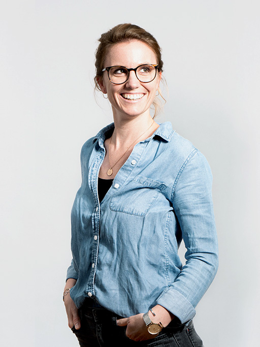 Bild einer Mitarbeiterin, die eine Jeans-Bluse trägt und die Hände in die Hosentasche steckt