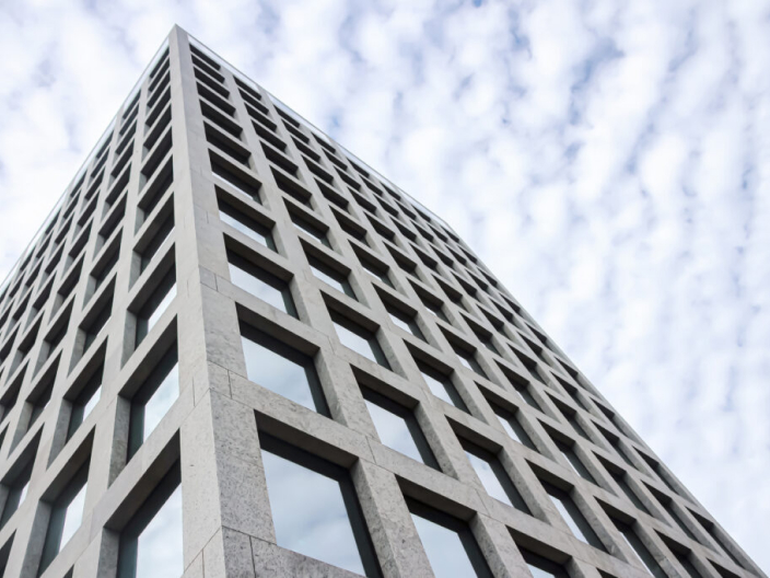 Ein Bild zeigt die IBM iX Niederlassung in Zürich. Das Gebäude ist aus grauem Beton mit vielen Fenstern.