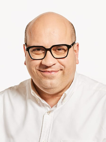 Man in white shirt in glasses, smiling.