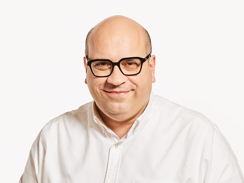 Man in white shirt in glasses, smiling.