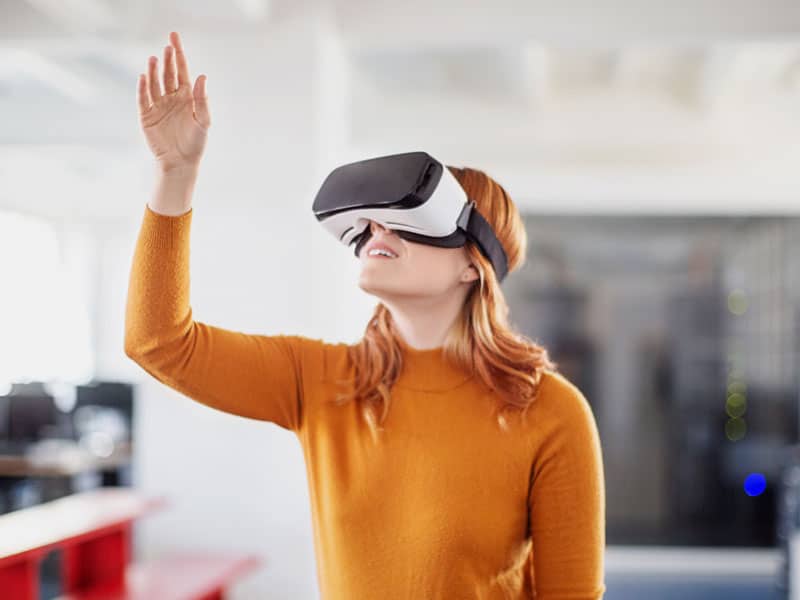 Woman reaching in the air with a VR headset