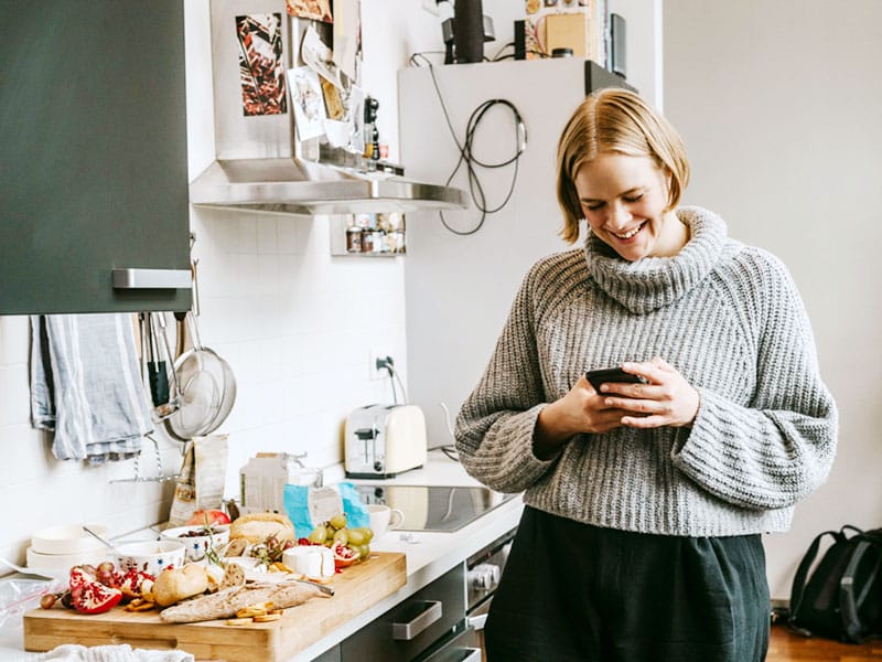 Woman in kitchen looking at mobile phone
