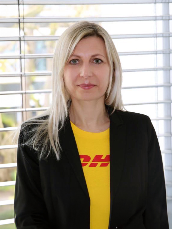 Woman in blazer and a yellow t-shirt showing the DHL logo.