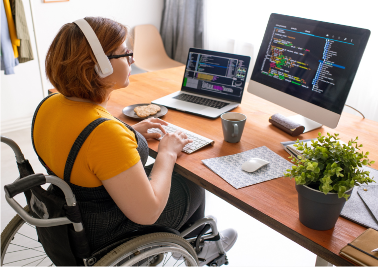 Eine im Rollstuhl sitzenden Person, die am Laptop arbeitet