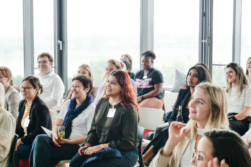 Vielfältige Personen auf einem Meetup, die sitzen und einer Präsentation zuhören.