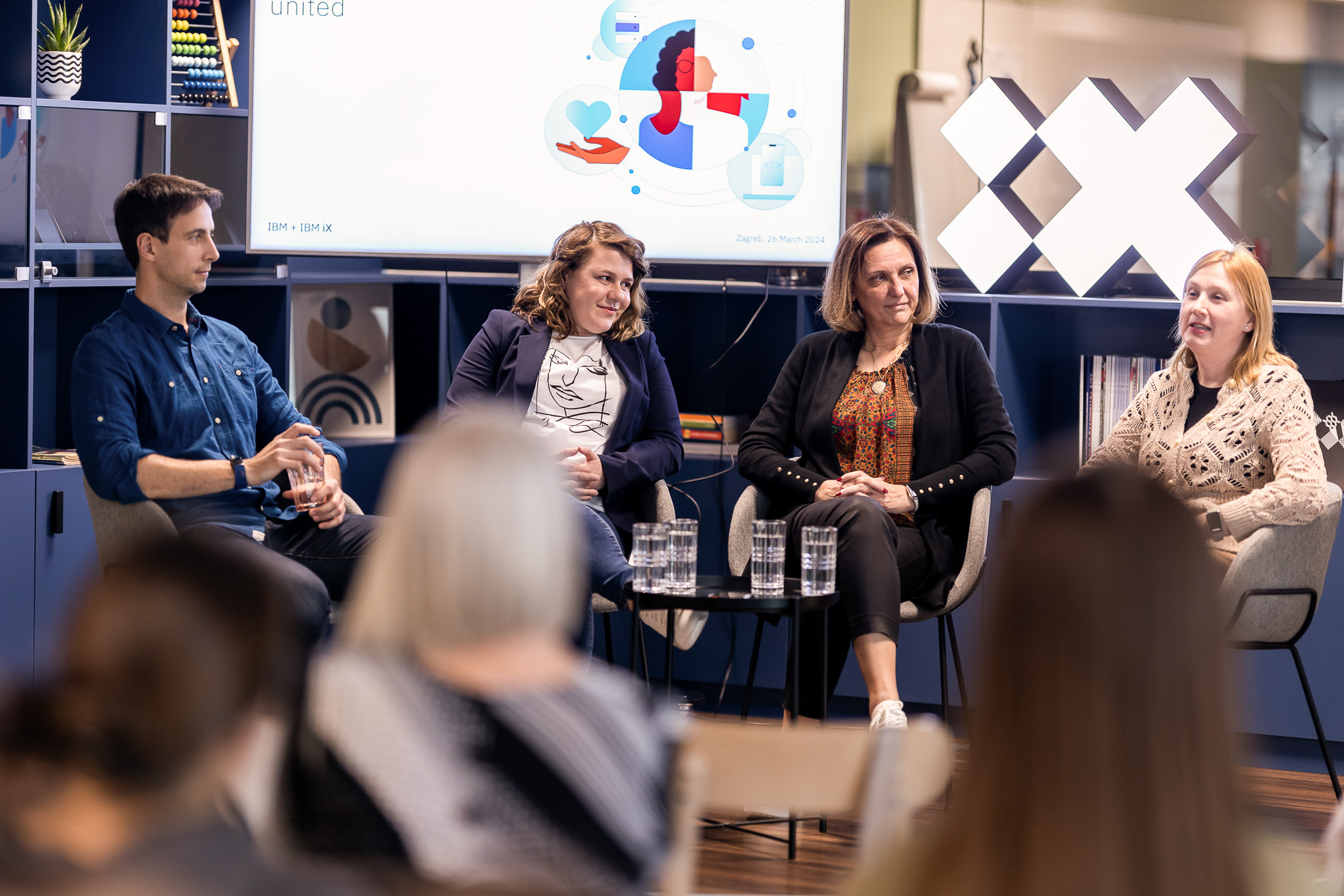 Drei Frauen und ein Mann auf einem Meetup-Event sitzen nebeneinander und führen ein Gespräch.