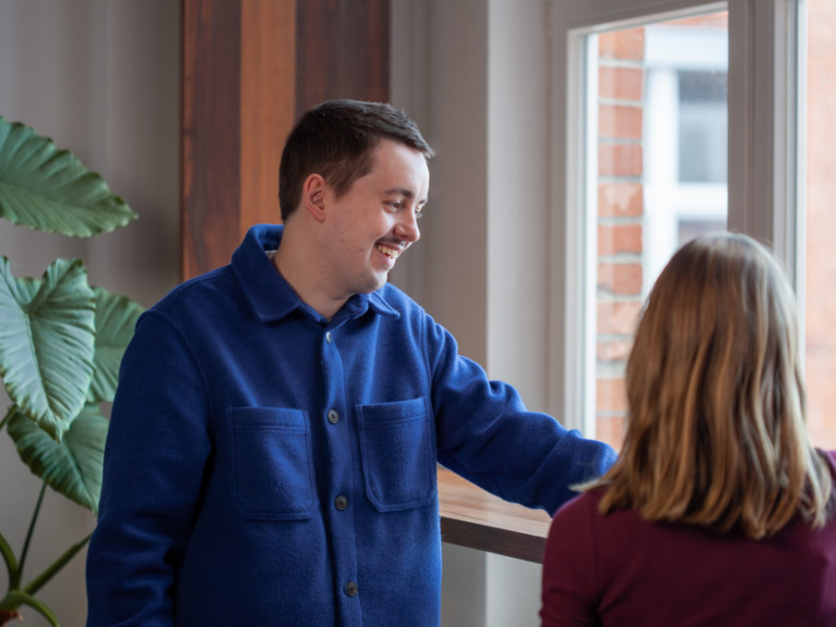 UI Designer Erik Lorenz is standing at a window and talking to a colleague
