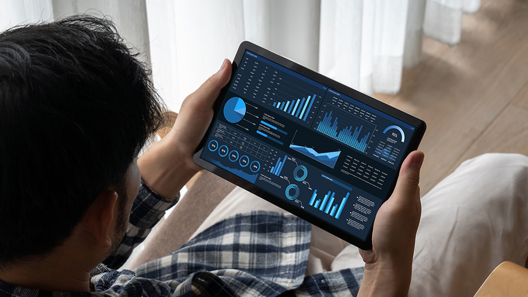 Person hält ein Tablet mit Datenvisualisierungen.