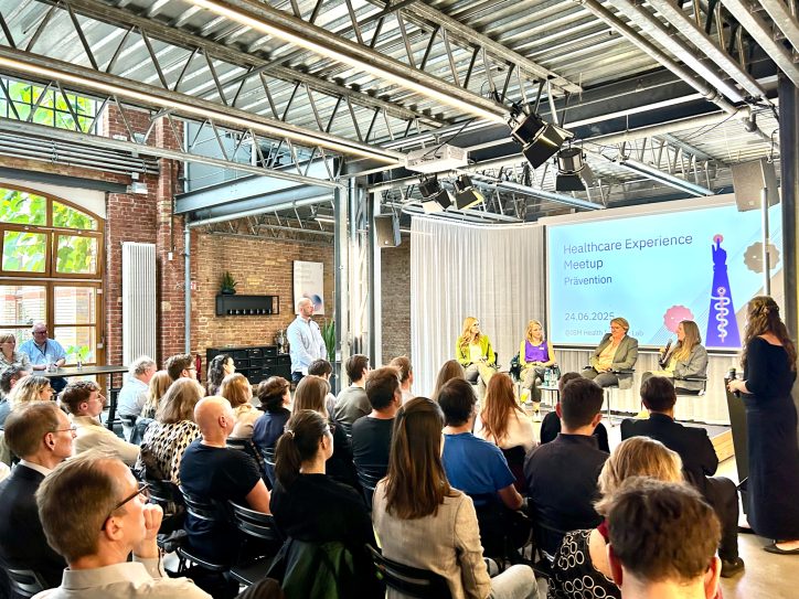 Mehrere Personen diskutieren auf der Bühne bei einem Healthcare Experience Meetup zum Thema Prävention, während das Publikum aufmerksam zuhört.