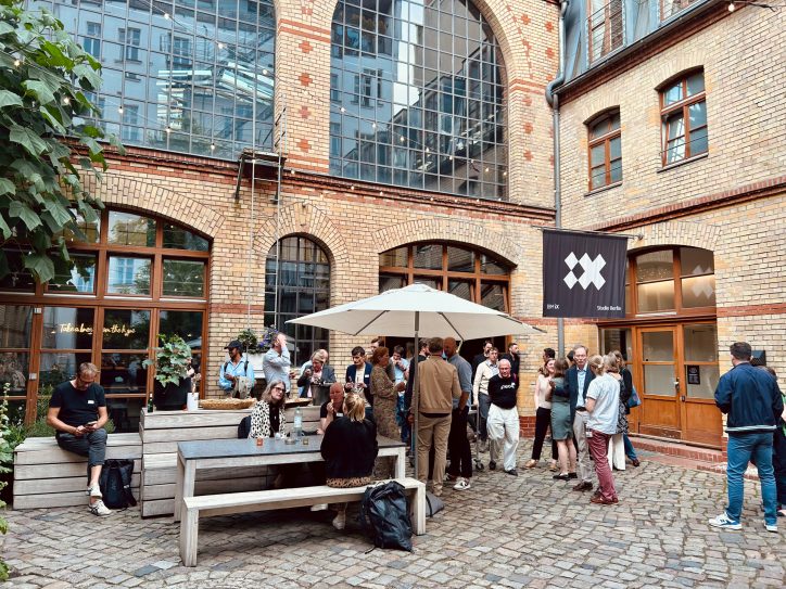 Ein lebhaftes Healthcare Meetup findet in einem charmanten Innenhof mit historischen Backsteingebäuden statt.