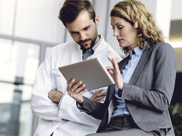Scientist and businesswoman discussing data on a tablet in a hallway