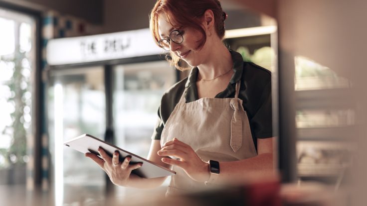 Employee using a tablet in a modern retail environment, showcasing IBM iX's transformation of customer experience for METRO worldwide.