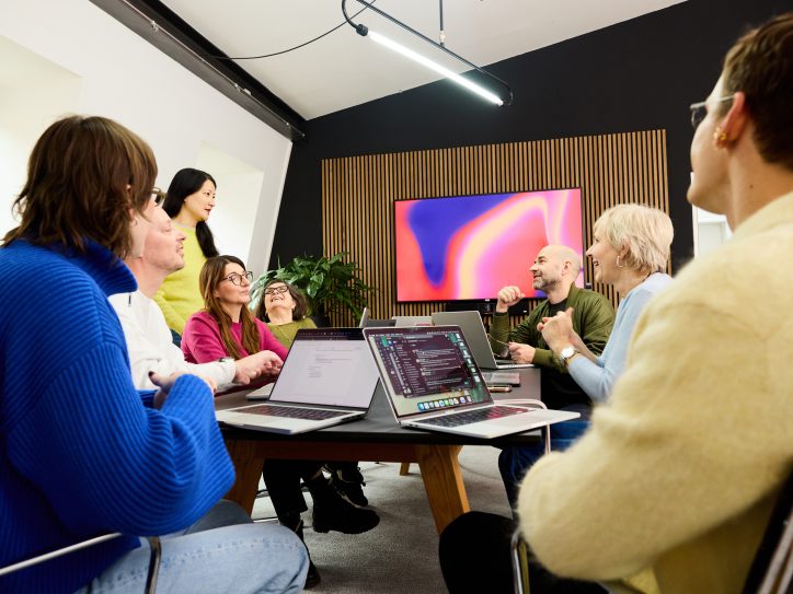 IBM iX Mitarbeitende, die in einem modernen Innovationsstudio an digitalen Experience‑Projekten zusammenarbeiten.