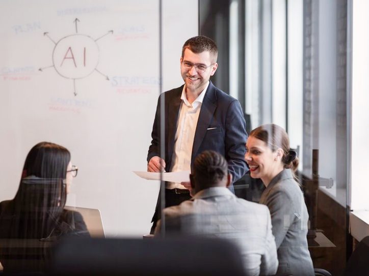 4 Personen bedinden sich in einen Meetingraum und besprechen sich