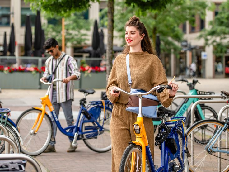 Fahrradfahrer nutzen Leihfahrräder in der Stadt und zeigen nahtlose multimodale Mobilität als Teil der Omni-Channel Customer Experience der Niederländischen Eisenbahn.
