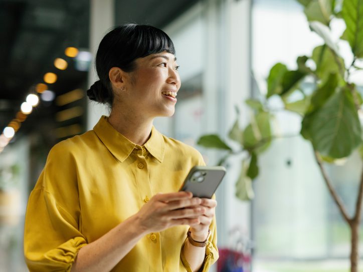 Frau mit Smartphone nutzt digitalen Kundenservice eines Energieversorgers in modernem Büro – Symbol für kundenorientierte Services im Energiesektor