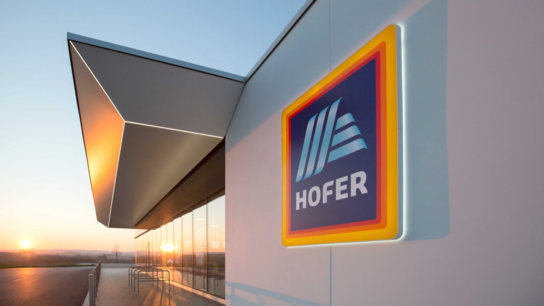 HOFER-Logo an der Fassade eines modernen Gebäudes bei Sonnenuntergang